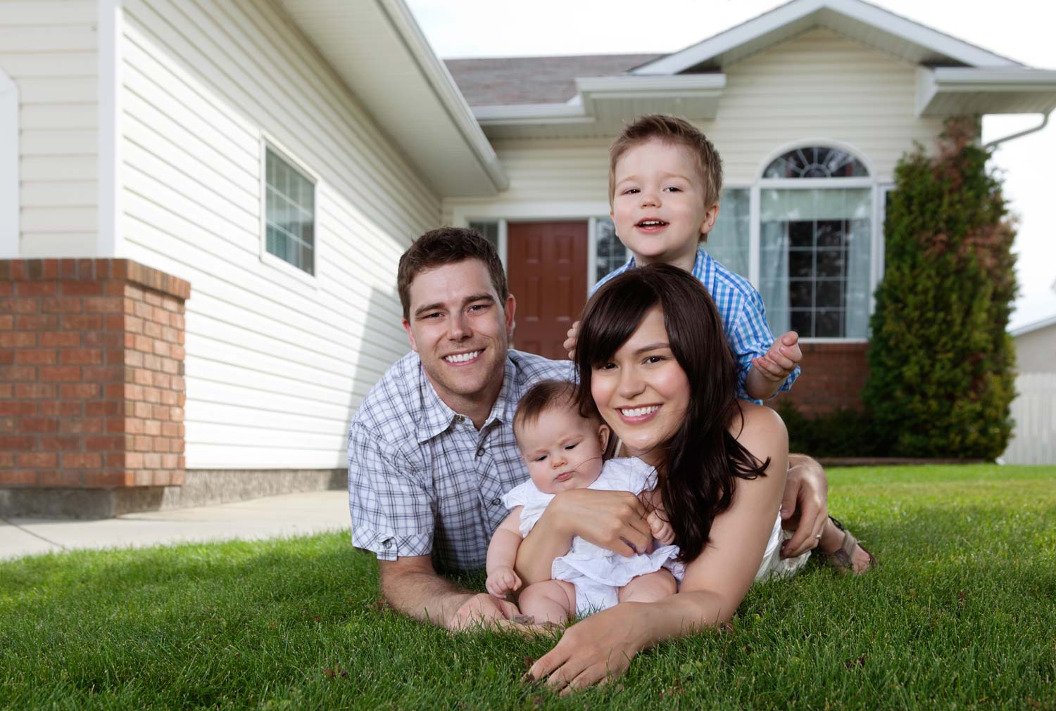young family with toddler and baby in front of home